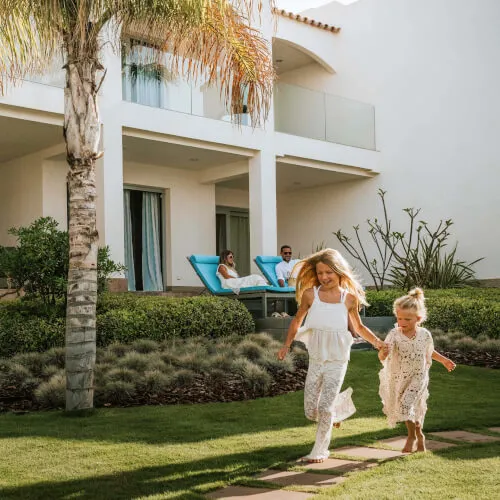 Two girls running joyfully on a path at 7Pines Resort Ibiza, perfect for family stays at The Laguna.