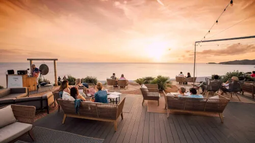 Grupo de personas disfrutando de una cena al atardecer con vistas al océano en 7Pines Resort Ibiza.