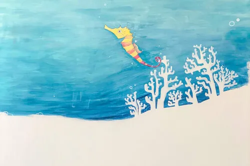 Child art depicting a seahorse and corals on a blue background at kio – house of kids.