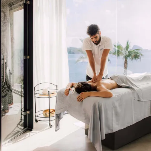 Una mujer disfrutando de un masaje personalizado en Pure Seven spa, 7Pines Resort Ibiza, incorporando la sal de Ibiza y hierbas locales.