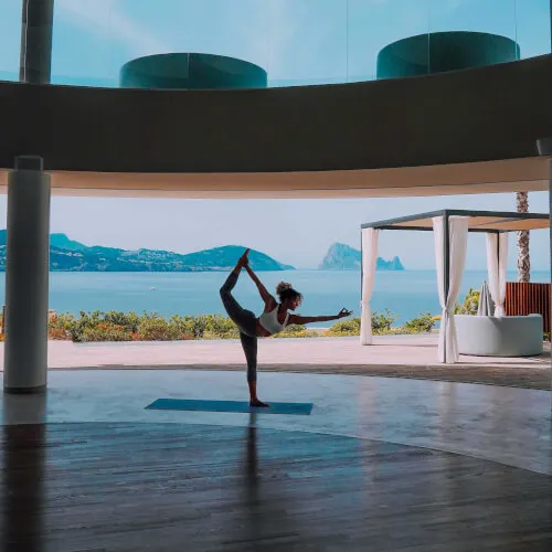 Mujer practicando yoga en 7Pines Resort Ibiza con la serena vista al mar.