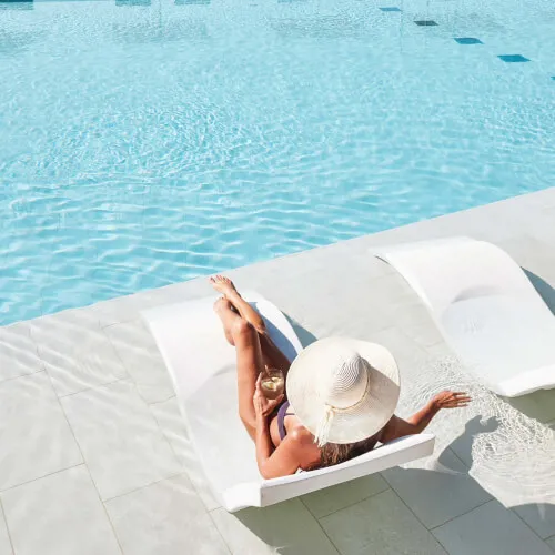 Frau entspannt auf einer Sonnenliege am Pool im 7Pines Resort Ibiza, dem perfekten Ort zum Baden und Sonnen.
