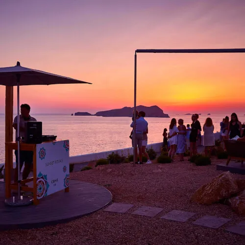 Grupo de personas disfrutando de la mágica puesta de sol en Cone Club, 7Pines Resort Ibiza, con vistas al mar y Es Vedrà.