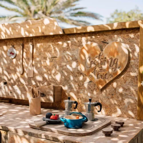 Ein Holztisch im 7Pines Resort Ibiza, der Nachhaltigkeitsaktivitäten wie Recycling und Gartenarbeit symbolisiert.