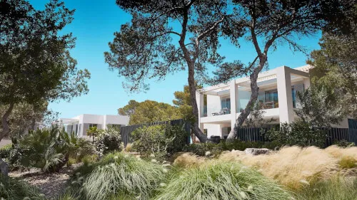 Ibicenco Village im 7Pines Resort Ibiza, umgeben von üppigem Grün und weiß getünchten Häusern.